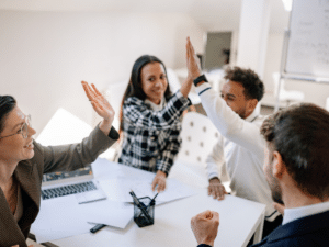 Employees high fiving, displaying the joy that comes with having group health insurance. 