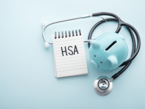 piggy bank next to a notepad with the word "HSA" written. 