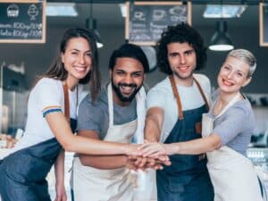 Group of happy small business employees standing together in a coffee shop